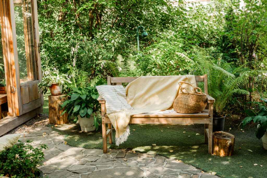 Geschützte Gartenbank mit Decke zwischen grünen Pflanzen